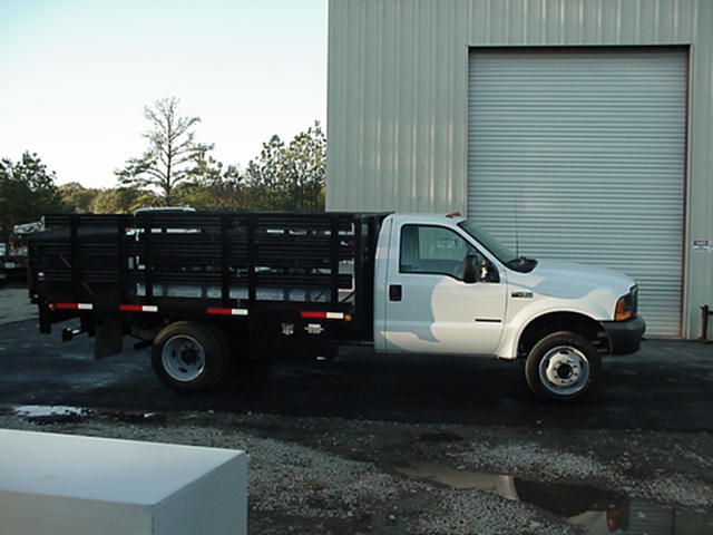 A white truck with a cage on the back is parked in front of a building