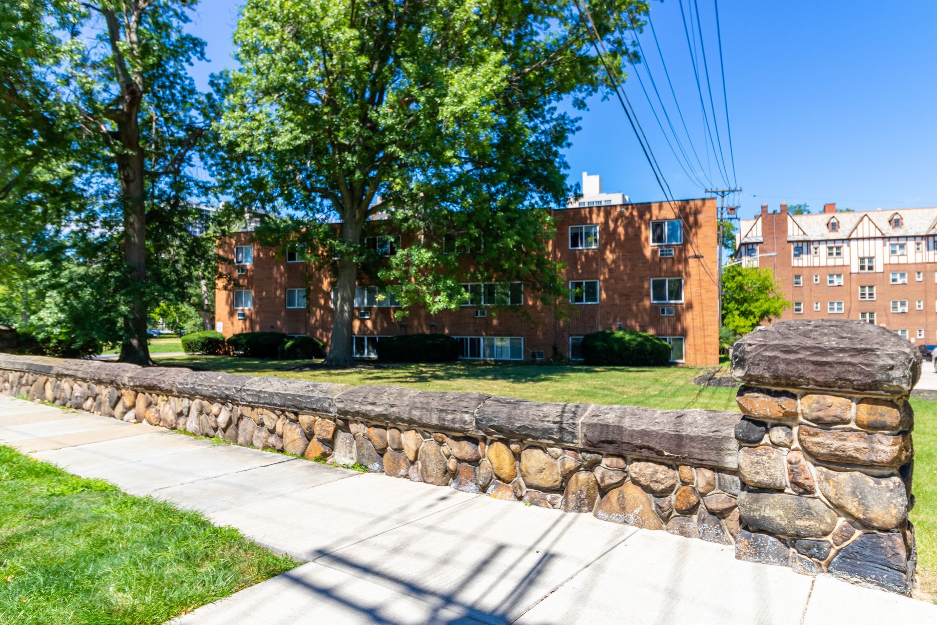 There is a stone wall between the sidewalk and the building.