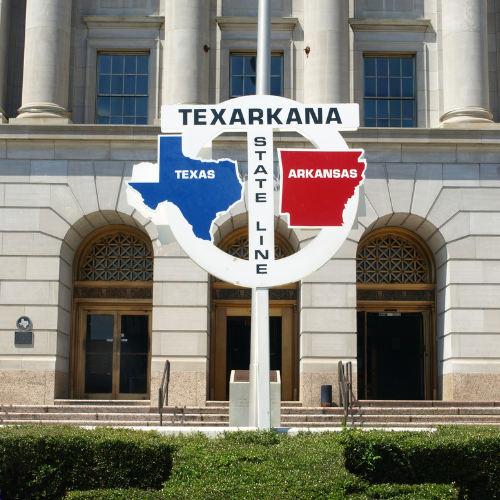 A texas and arkansas state line sign in front of a building