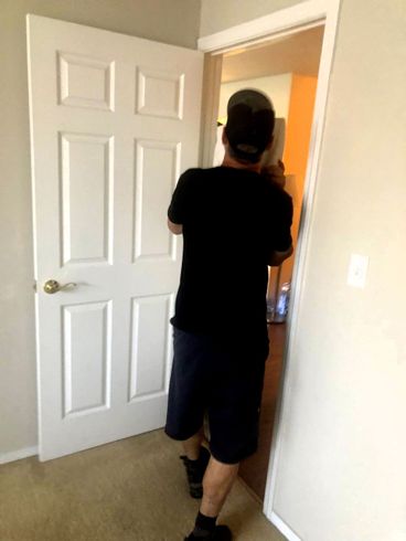 A man in a black shirt is standing in front of a white door