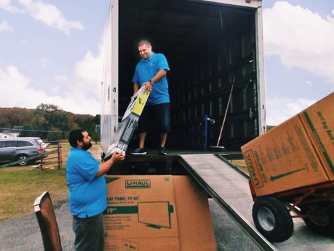 Two men are loading a ladder into a moving truck