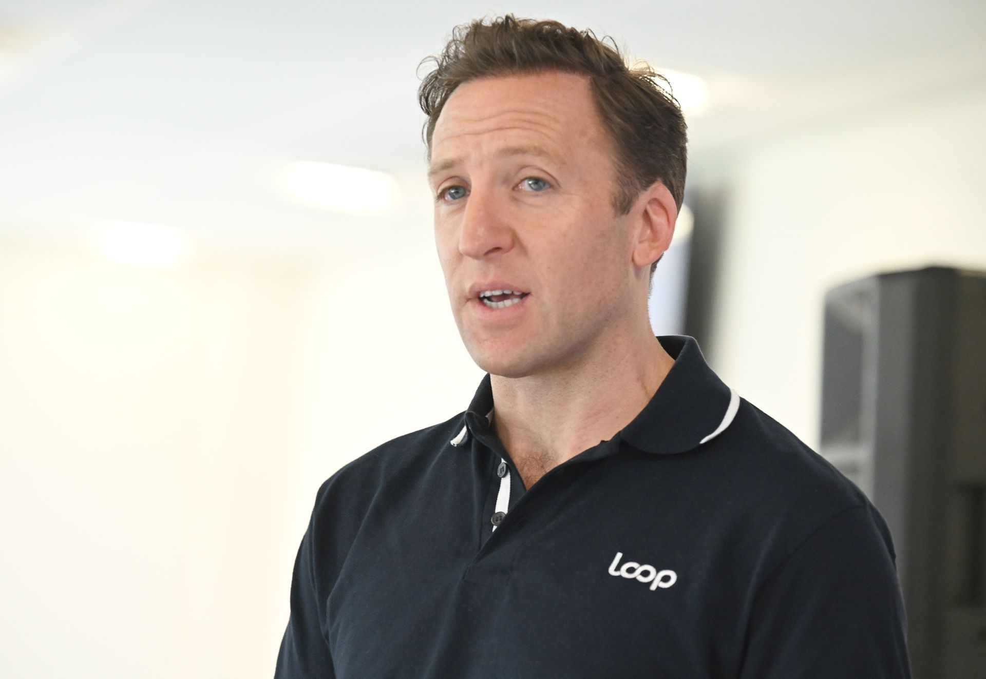 A row of desks and chairs in an office with a green wall behind them.