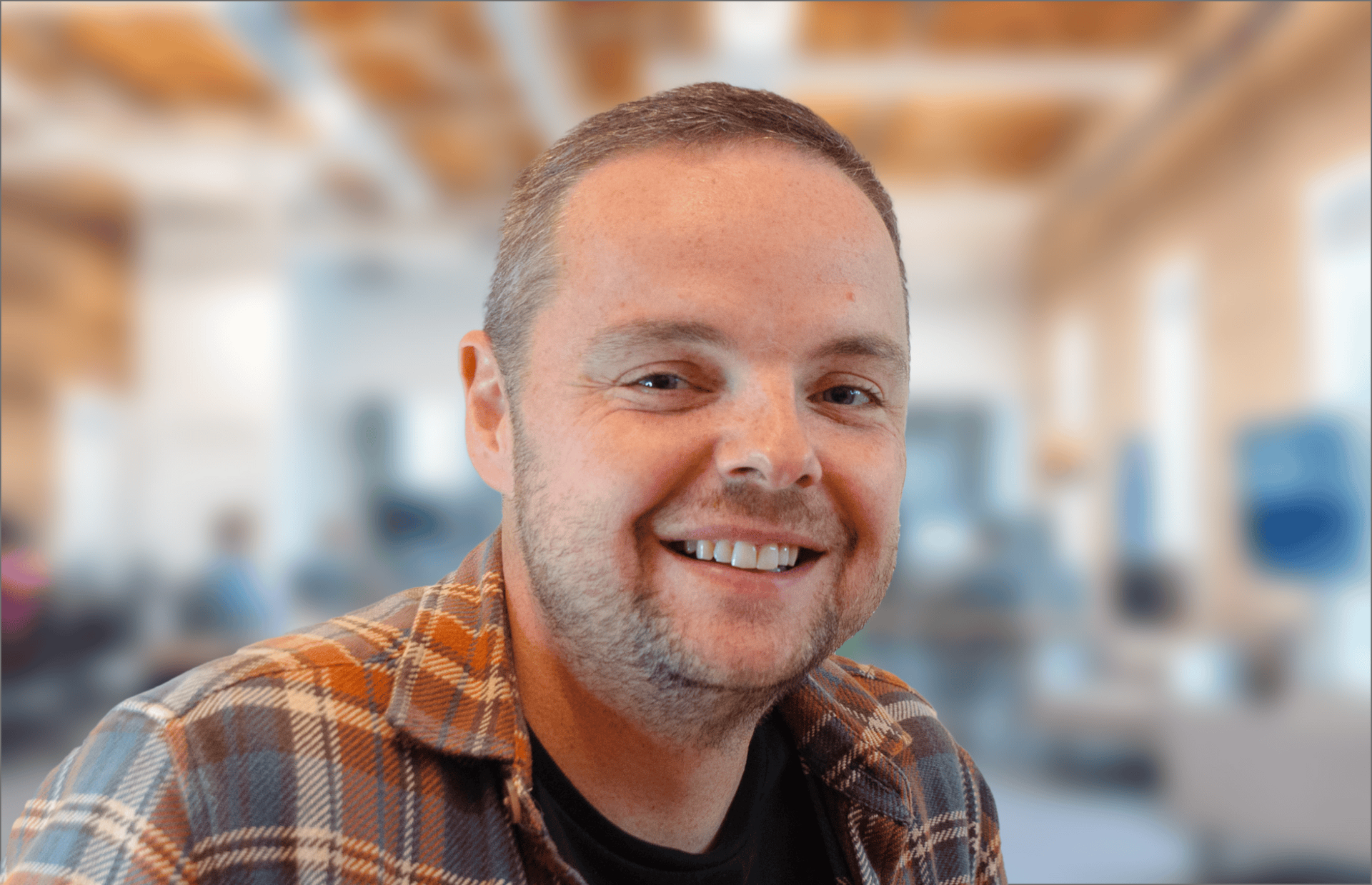 A man in a plaid shirt is smiling for the camera.