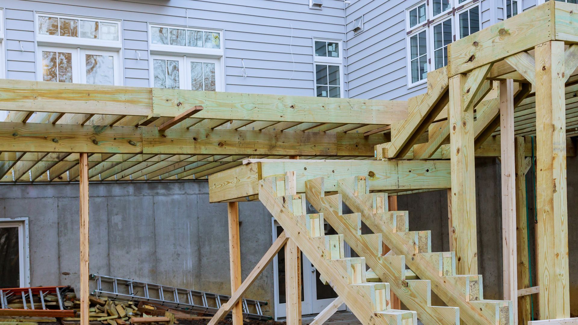 A wooden deck and stairs are being built in front of a house.