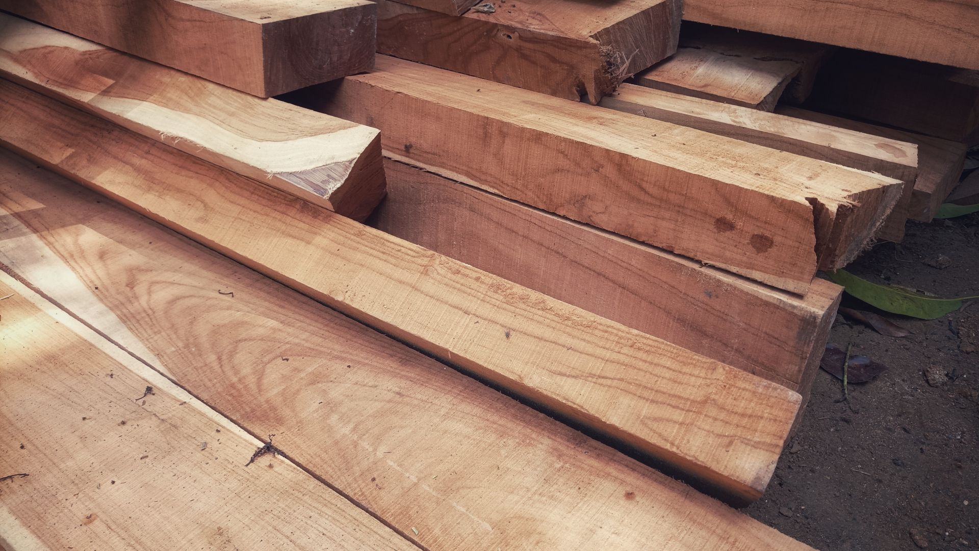 A pile of wood sitting on top of each other on the ground.