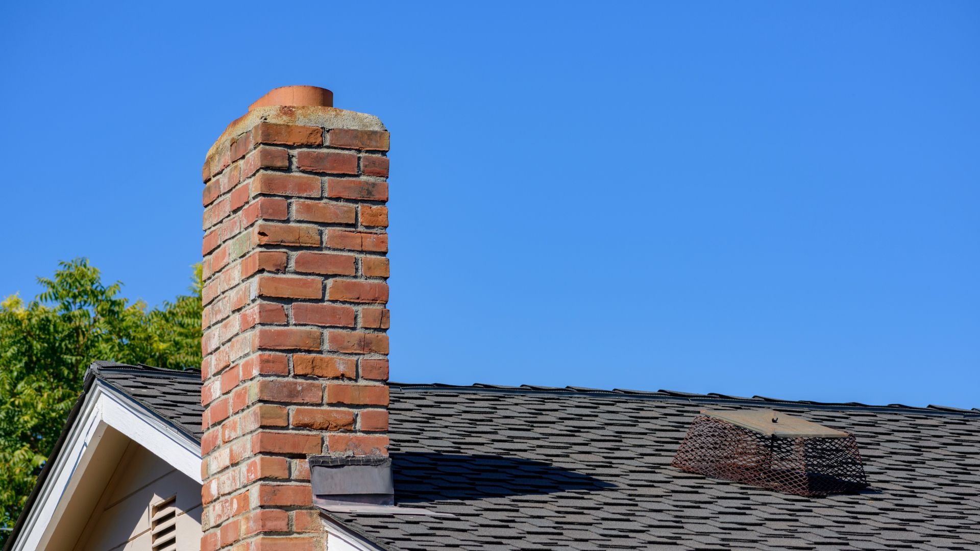 A brick chimney on top of a roof of a house.