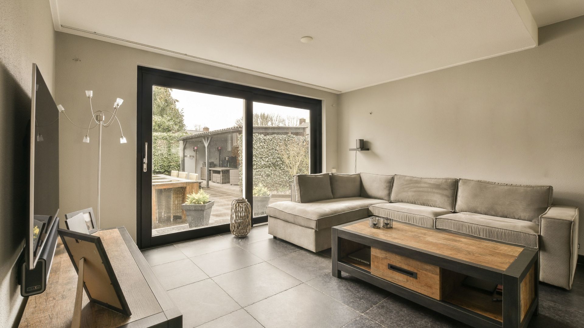 A living room with a couch , coffee table , television and sliding glass doors.