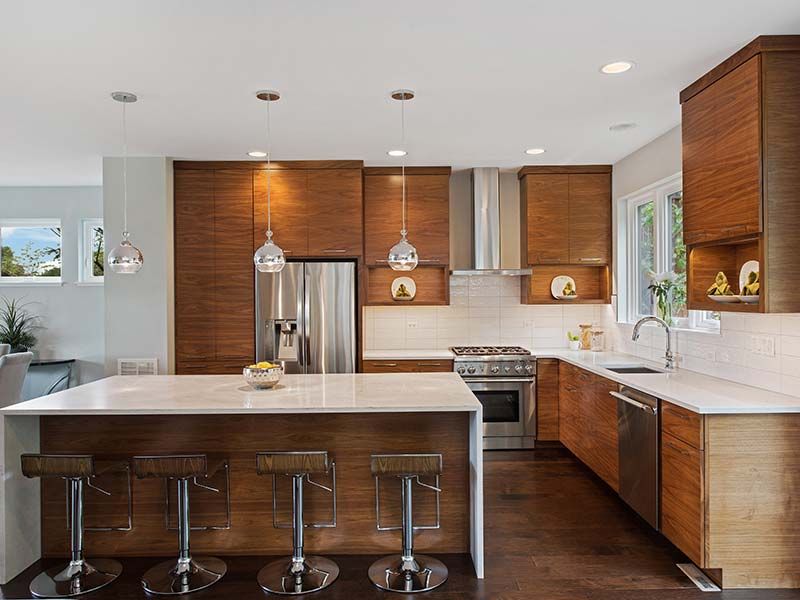 A kitchen with wooden cabinets , stainless steel appliances , and a large island.
