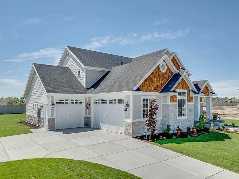 A large white house with a gray roof is sitting on top of a lush green lawn.