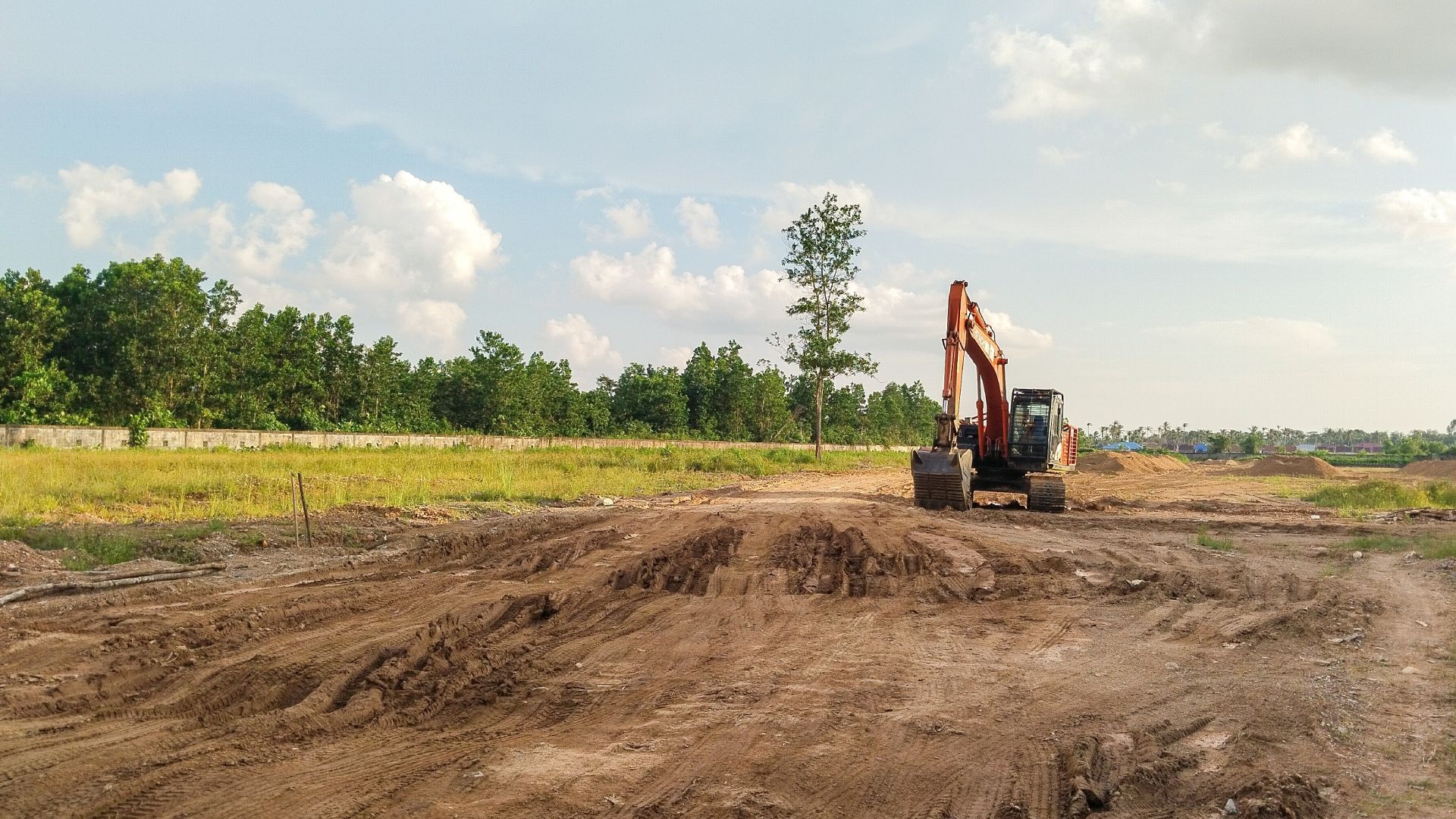 A bulldozer is moving dirt in a field with trees in the background.