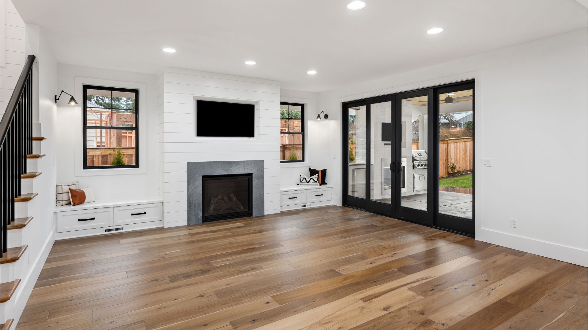 An empty living room with hardwood floors , a fireplace and a flat screen tv.