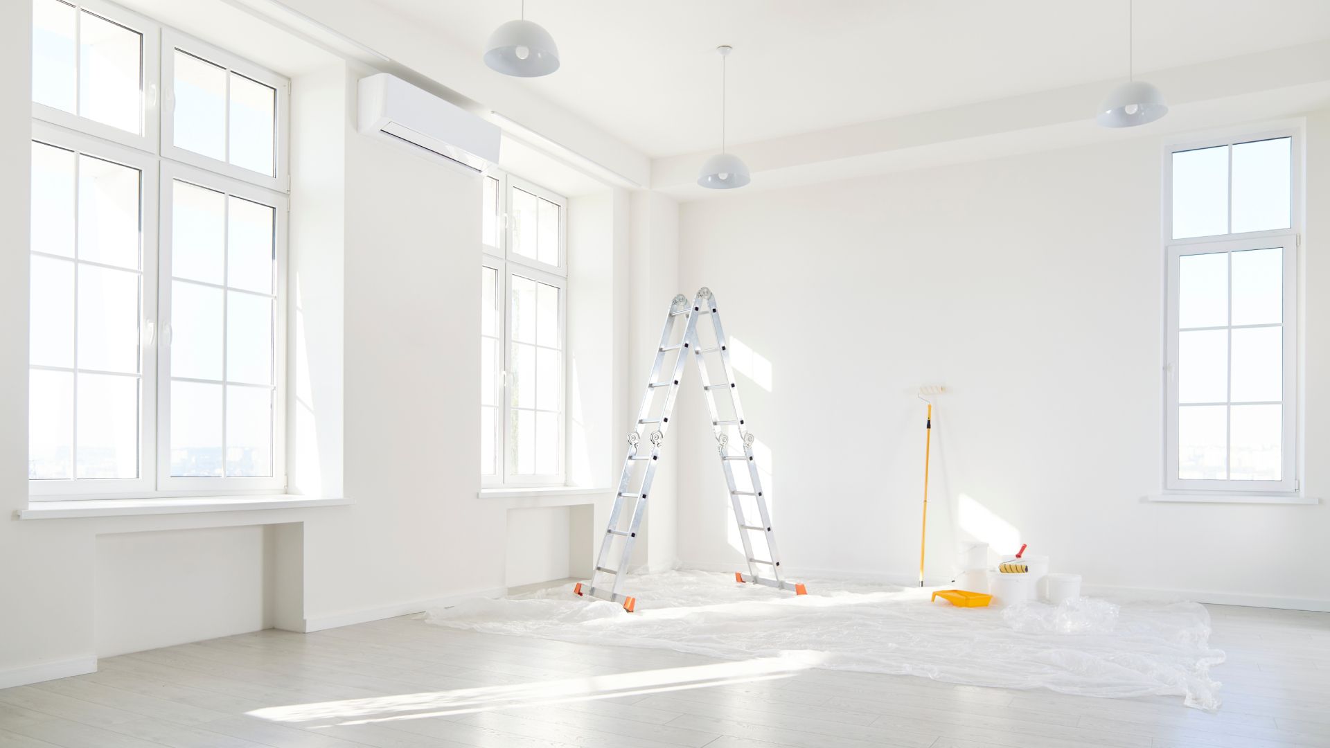 An empty room with a ladder and a mop in it.