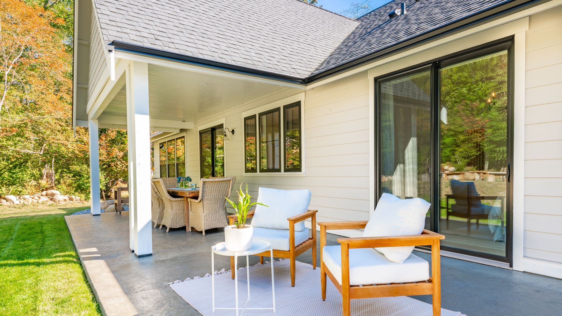 A white house with a patio with chairs and a table.