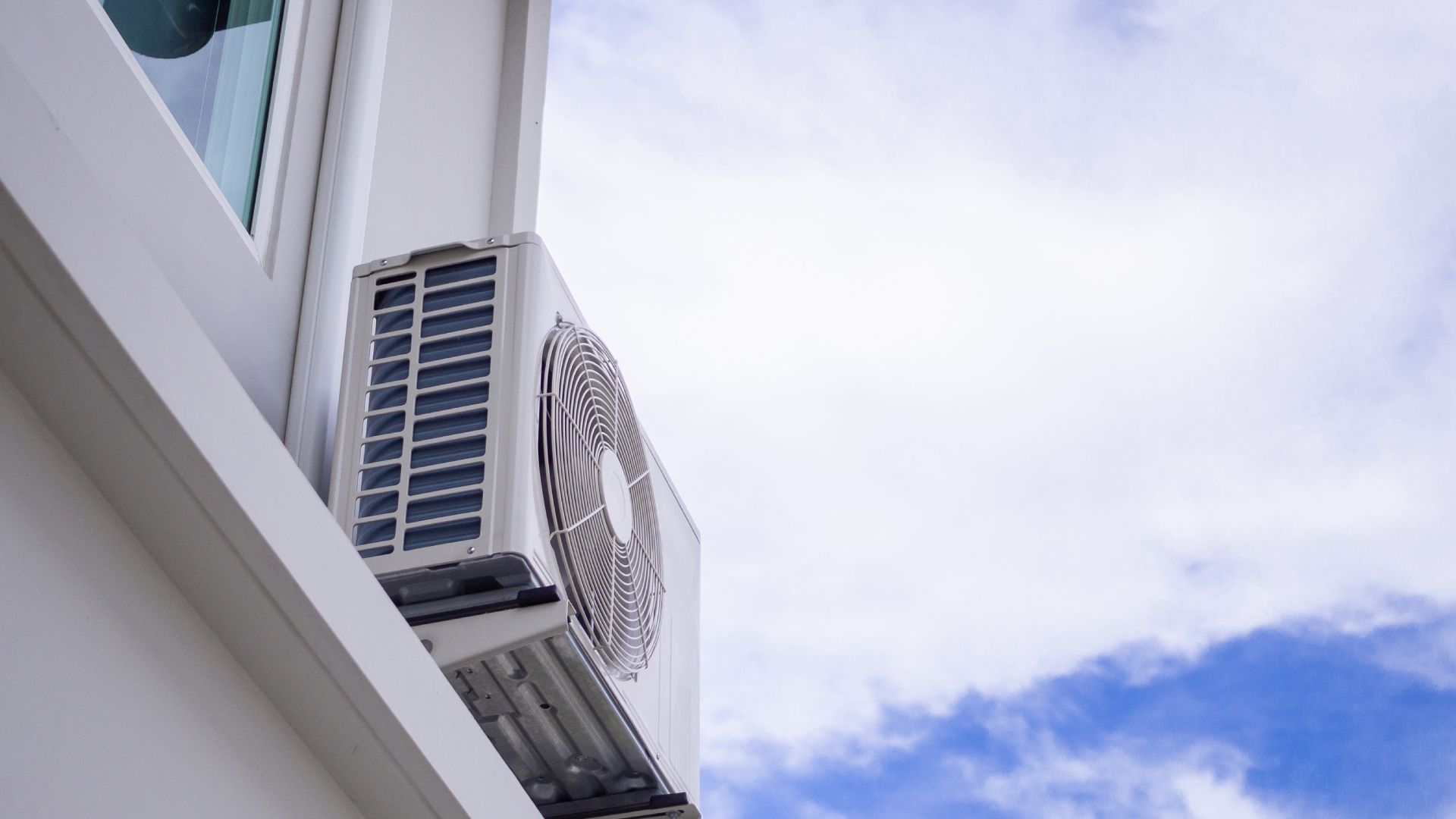 A white air conditioner is mounted on the side of a building.