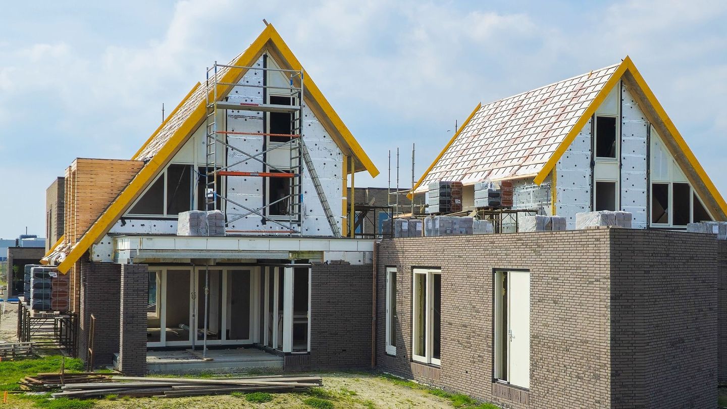 A couple of houses that are being built with a yellow roof