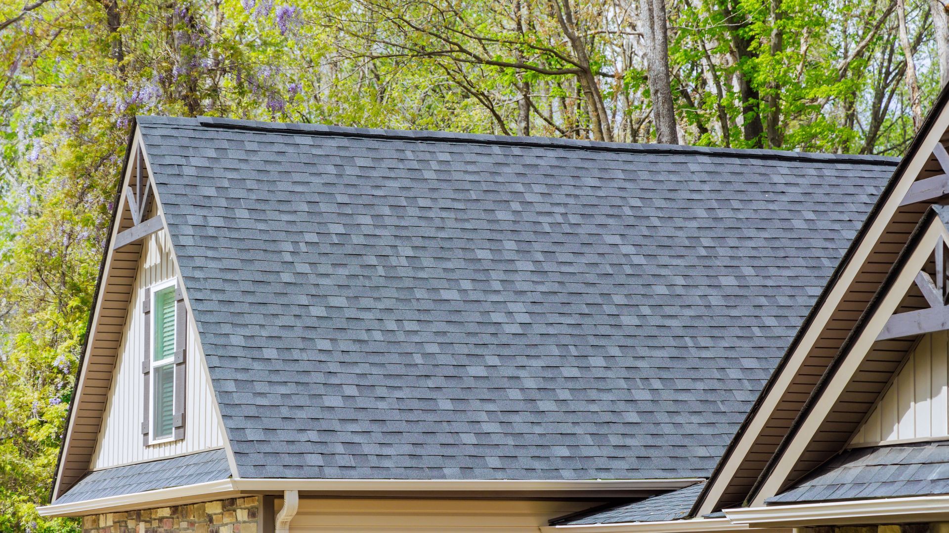 A close up of a house with a roof and trees in the background.