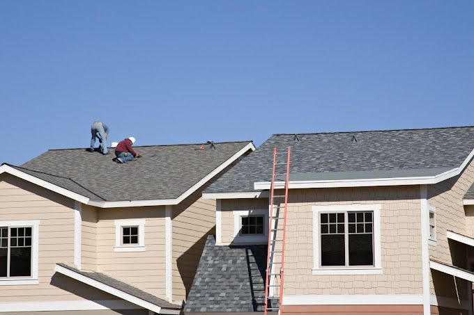 Two men are working on the roof of a house.