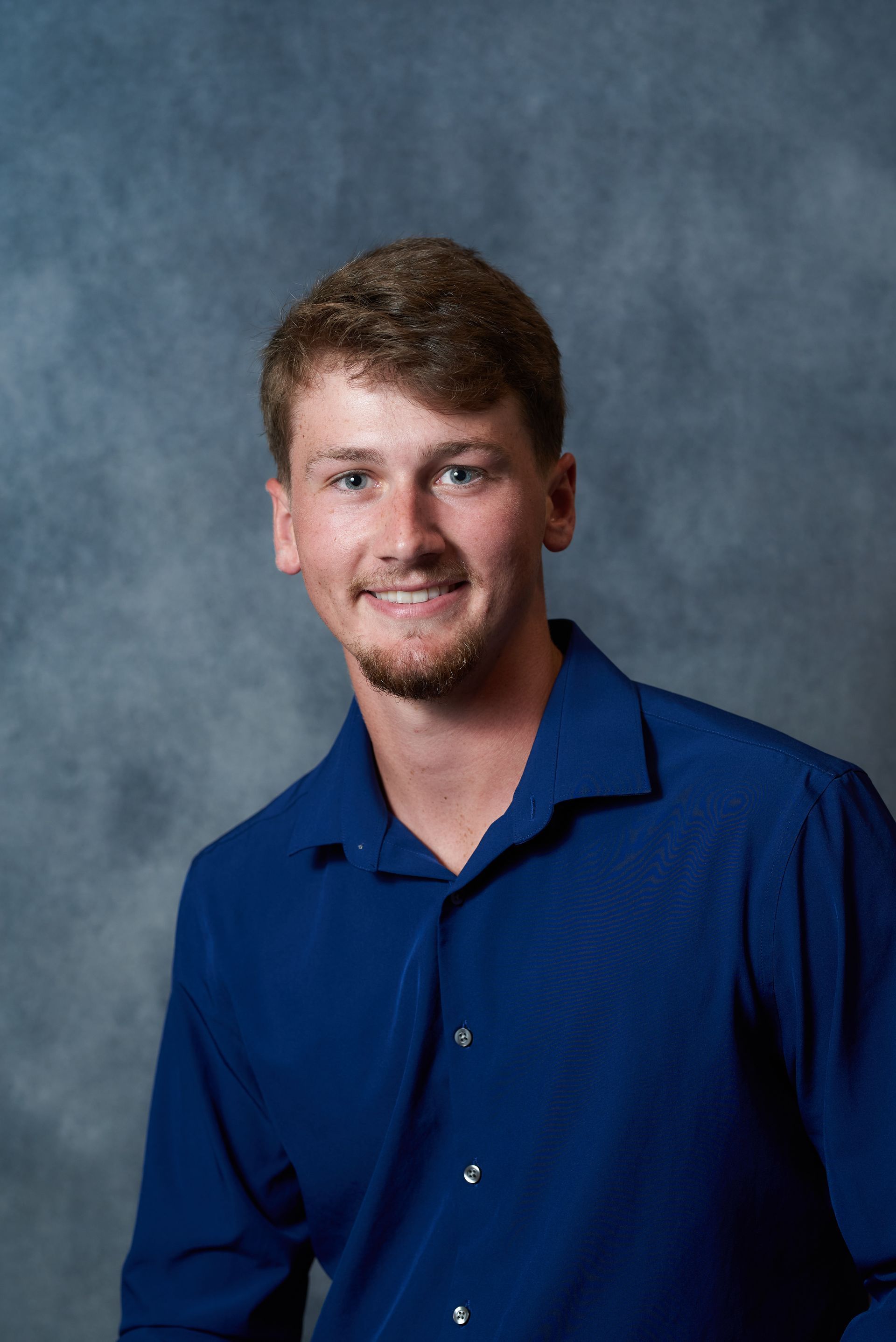 Smiling person in a blue shirt against a mottled blue background.