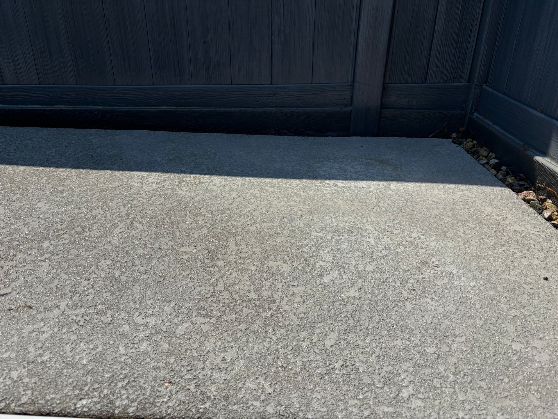 Concrete patio against a dark wood fence.