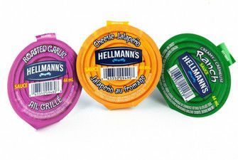 Three containers of hellmann 's sauce are sitting next to each other on a table.