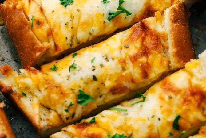 A close up of garlic cheese bread sticks on a pan.