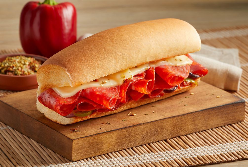 A sub sandwich is sitting on a wooden cutting board.