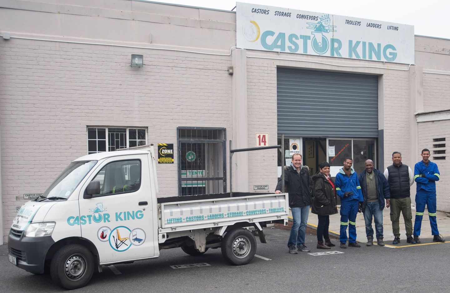 company truck and 5 staff members standing in front of a warehouse