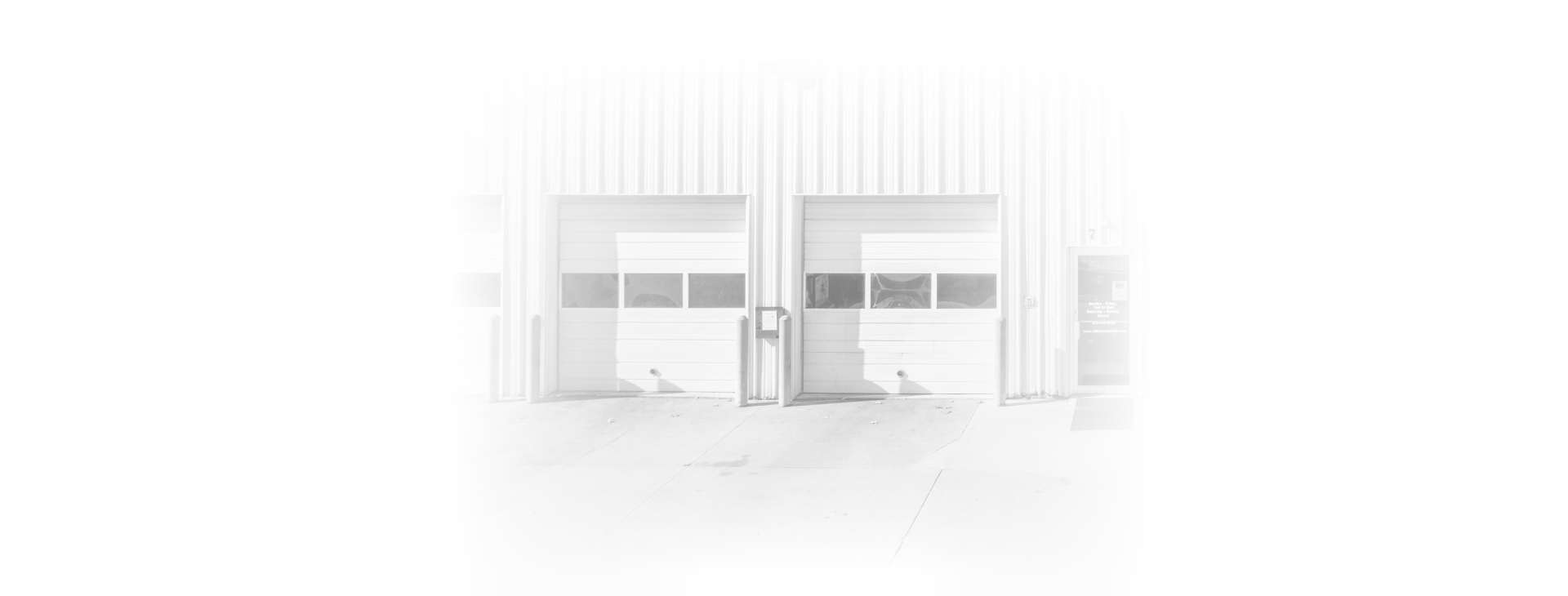 A black and white photo of a building with a lot of garage doors | All-Star Automotive