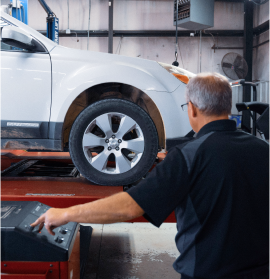 A man in a blue shirt is working on a car wheel | All-Star Automotive