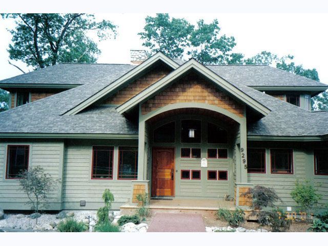 Green house with brown trim and roof, arched entryway.