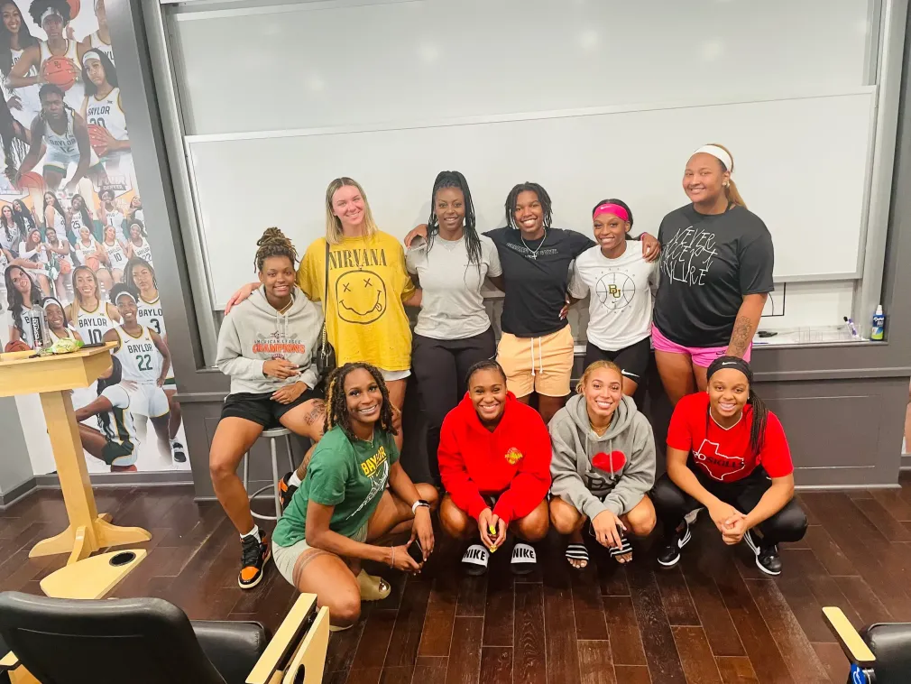 A group of young women are posing for a picture in a classroom.