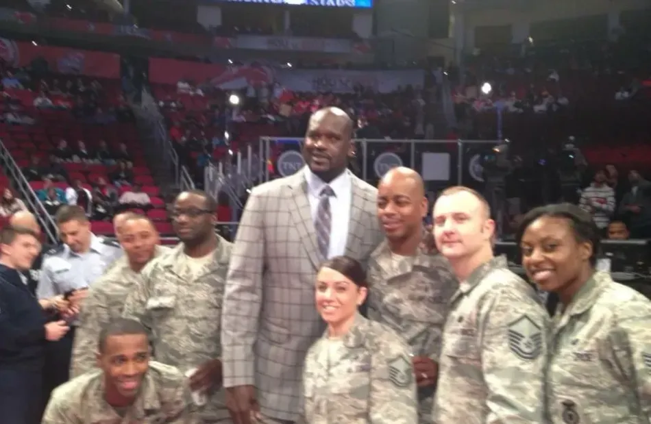 A group of soldiers are posing for a picture with a man in a suit