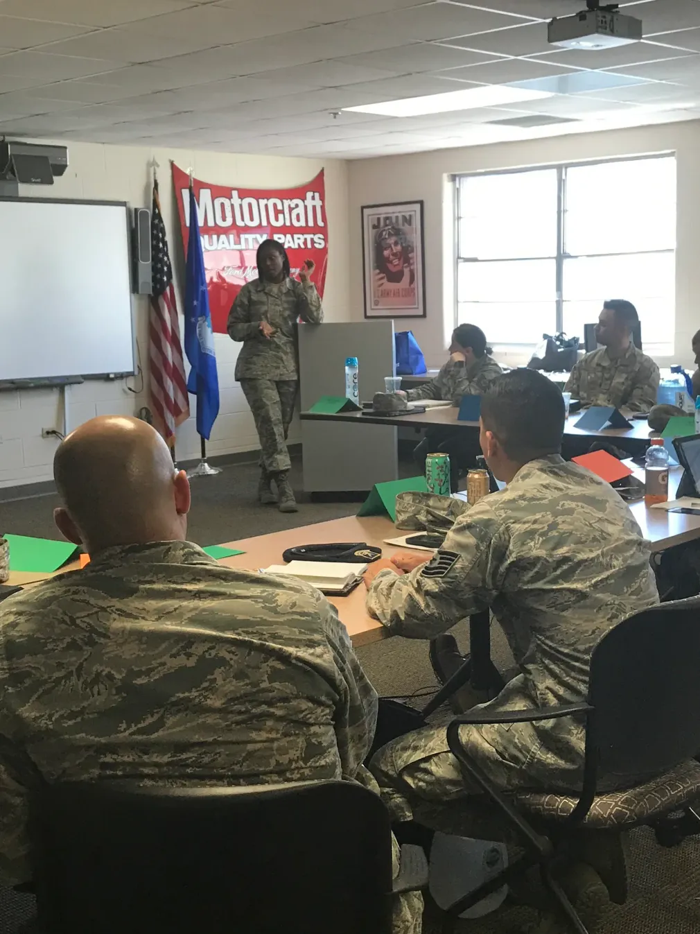A group of soldiers are sitting around a table in front of a motorcraft sign