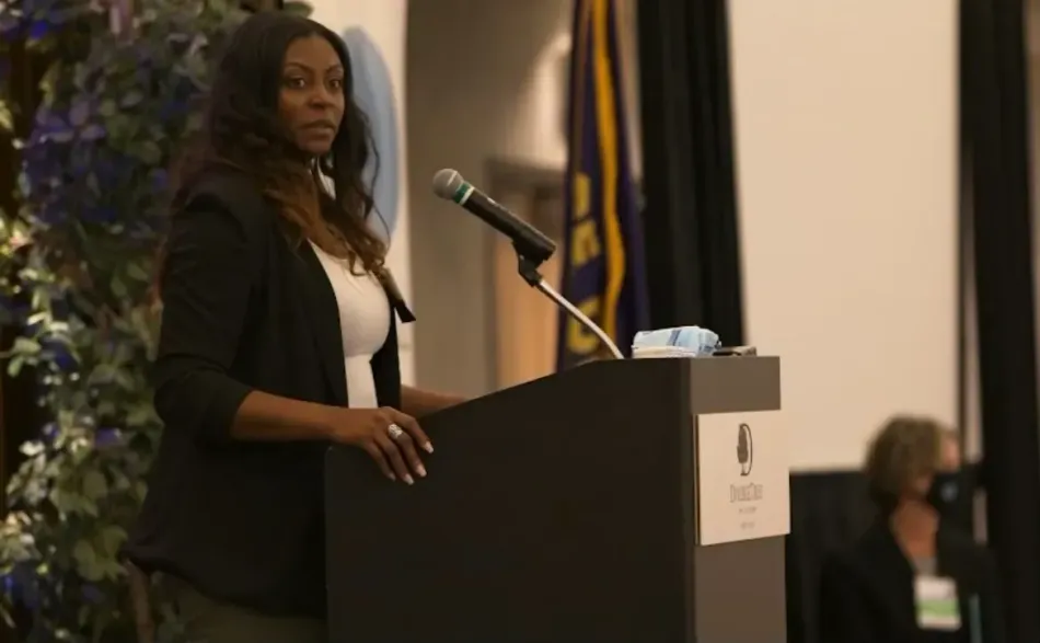 A woman is standing at a podium speaking into a microphone.