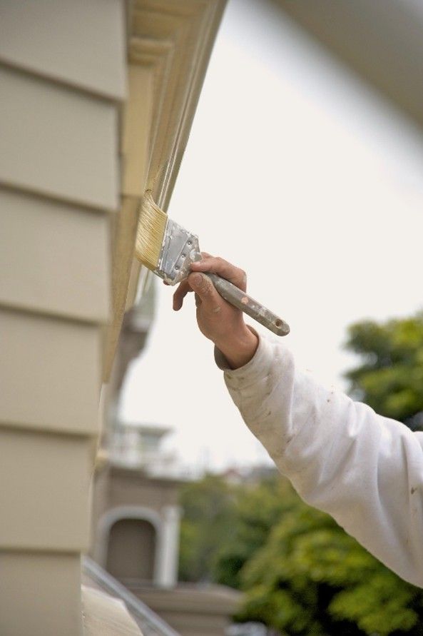Man applying fresh paint on exterior of house. Man applying fresh paint on exterior of house.
