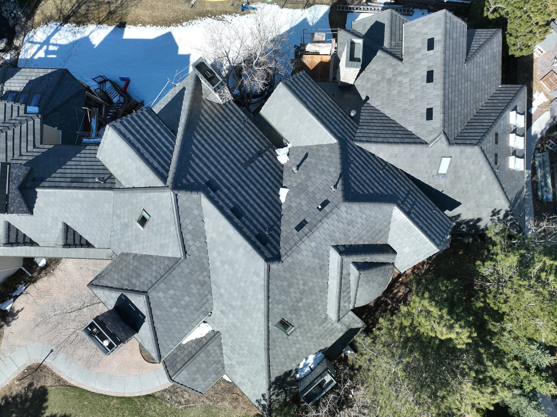 Residential Roofing Contractor inspecting a large multi-section shingle roof on a custom home from a
