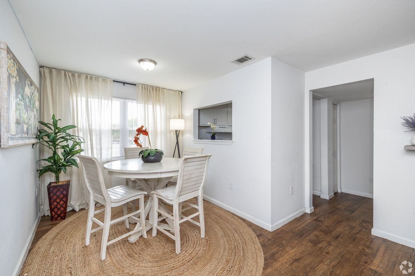 Dining room in apartment home with plants and an eating area and a window to see into the kitchen