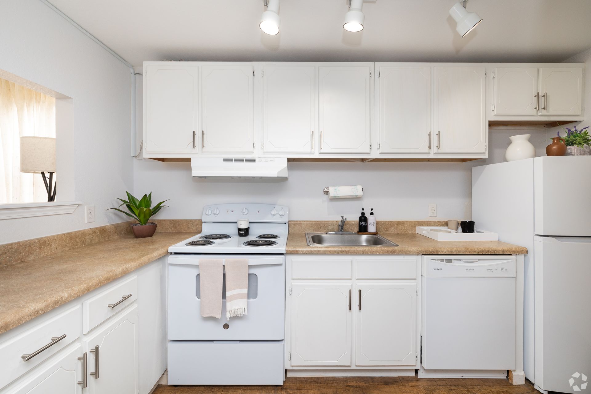 Apartment kitchen with large countertops and white cabinets and accessories