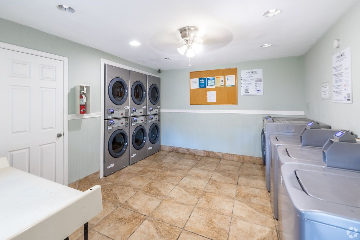 laundry facility with washers and dryers and a corkboard with property updates