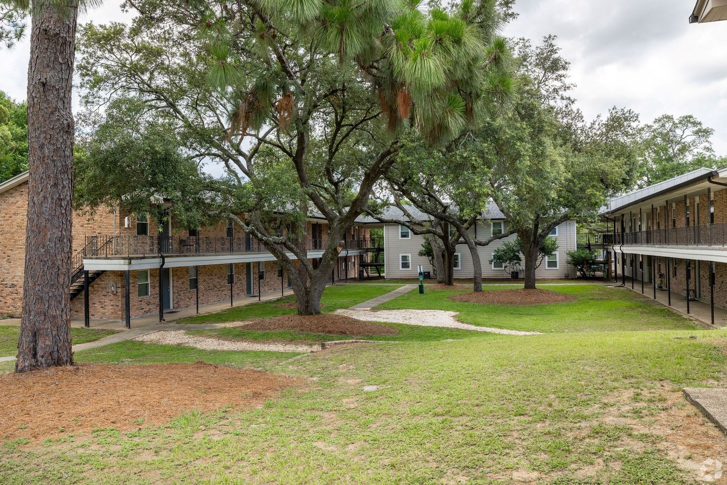 An open green courtyard area with sidewalk for walking area brick apartment complex