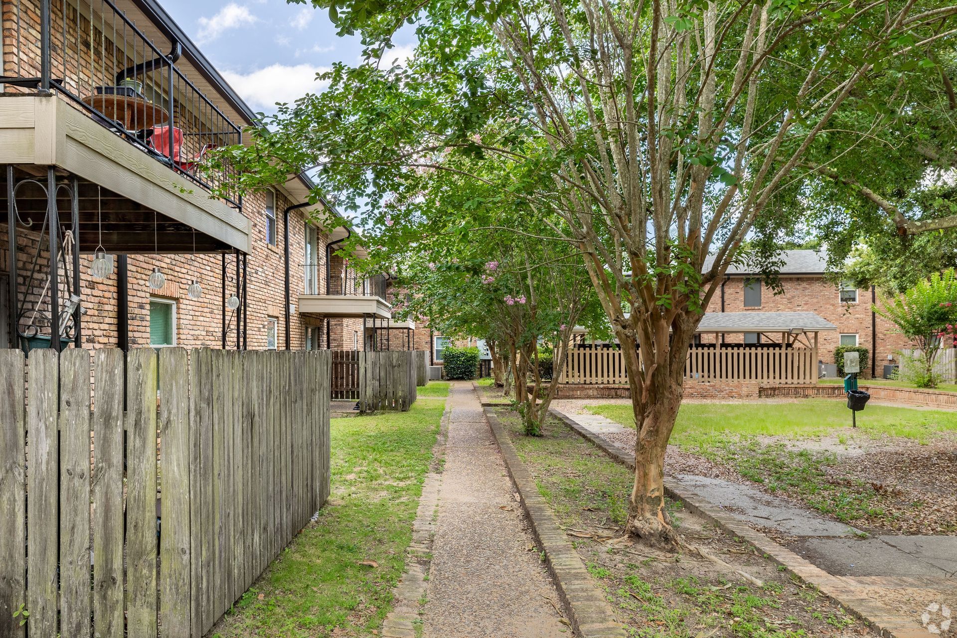 Brick apartment building with patios and balconies with a lush green lawn space