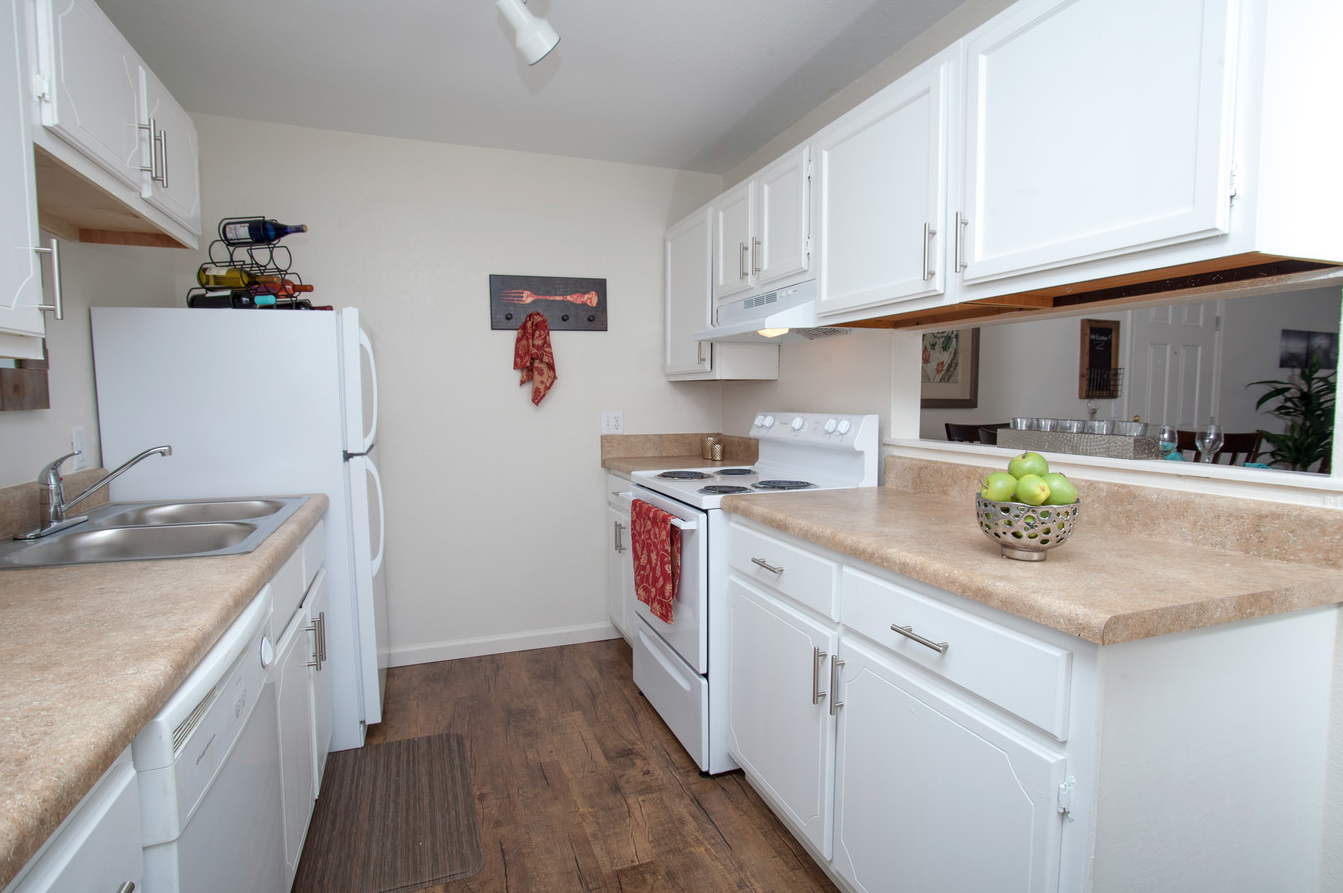 A kitchen with white cabinets , a refrigerator , a stove , and a sink.