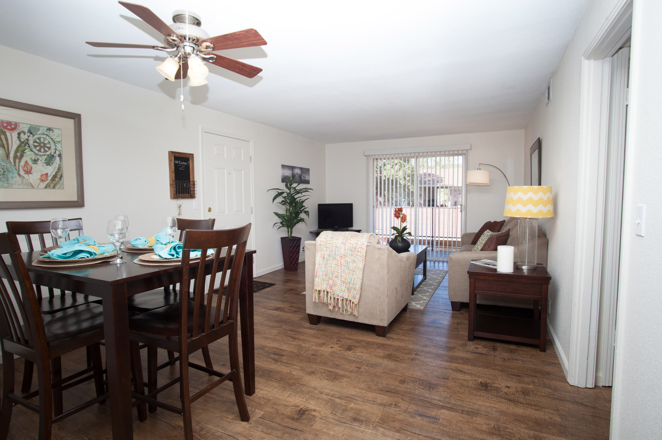 A living room with a table and chairs and a ceiling fan