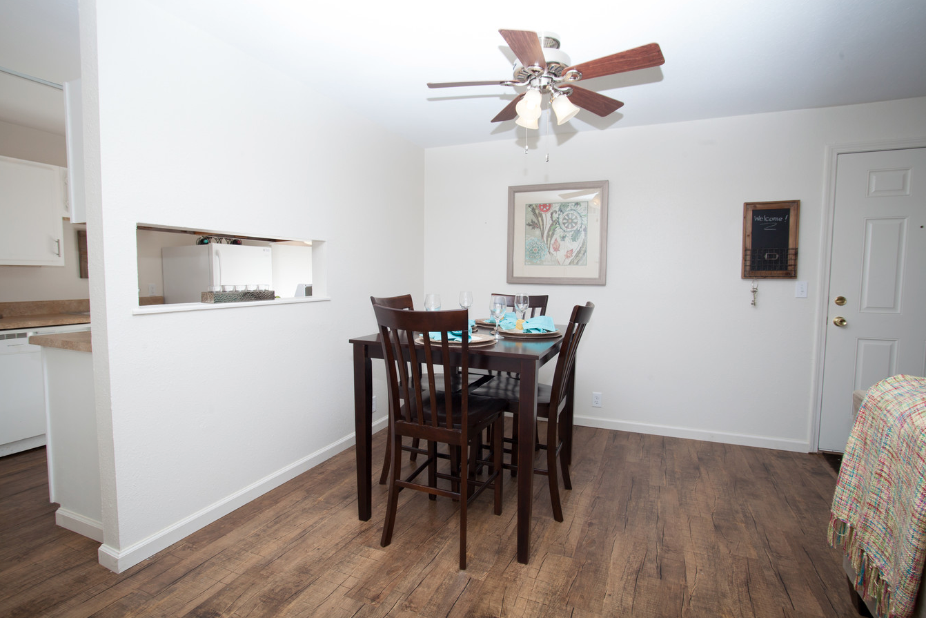 A dining room with a table and chairs and a ceiling fan.