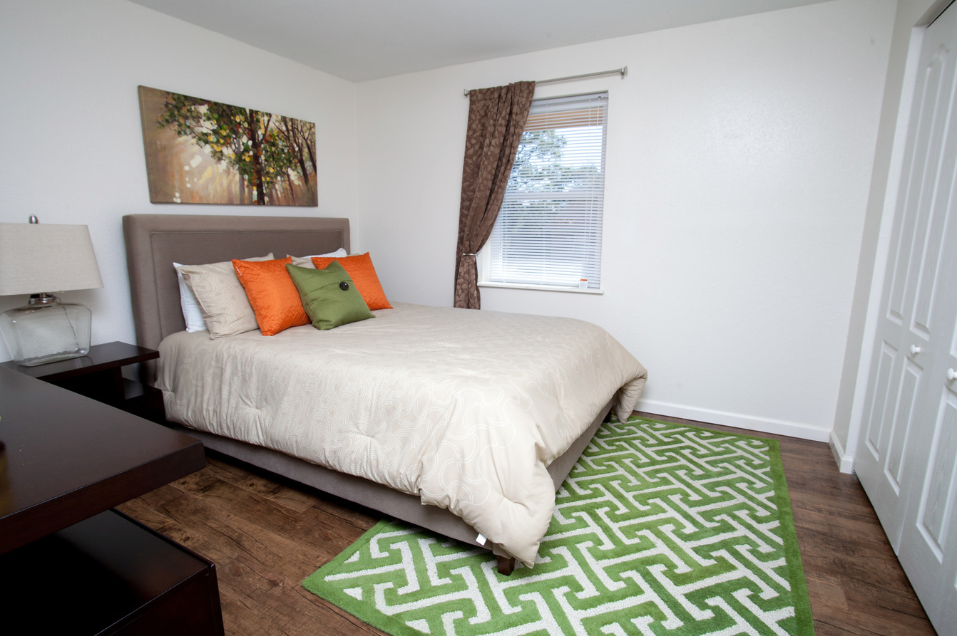 A bedroom with a bed and a green rug