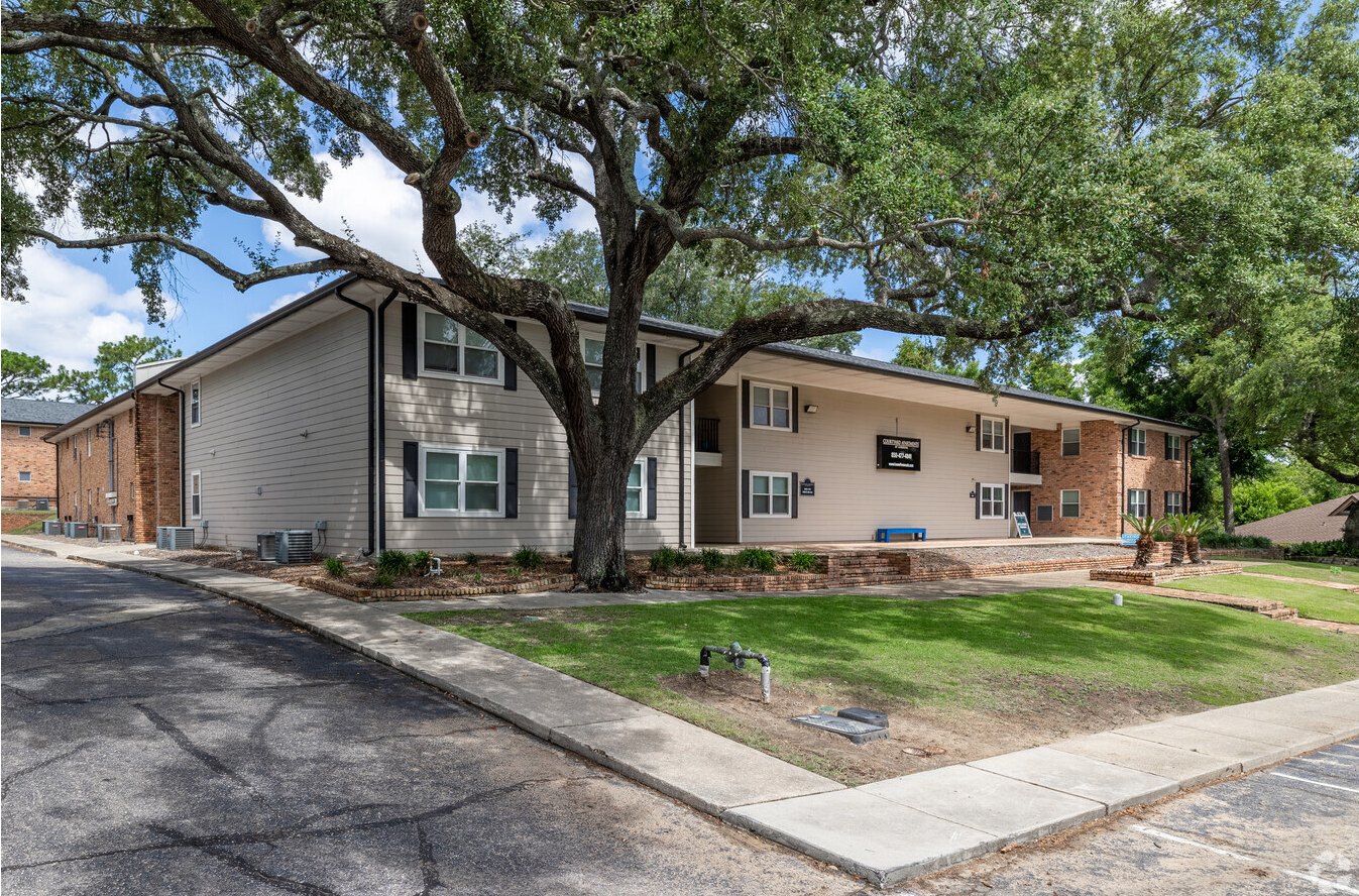 A large apartment building with a tree in front of it.