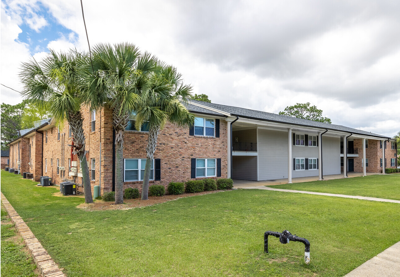 A large brick apartment building with a lush green lawn in front of it.