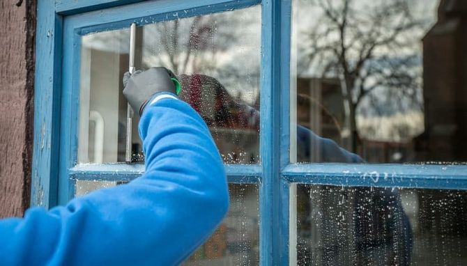 A person is cleaning a window with a brush.