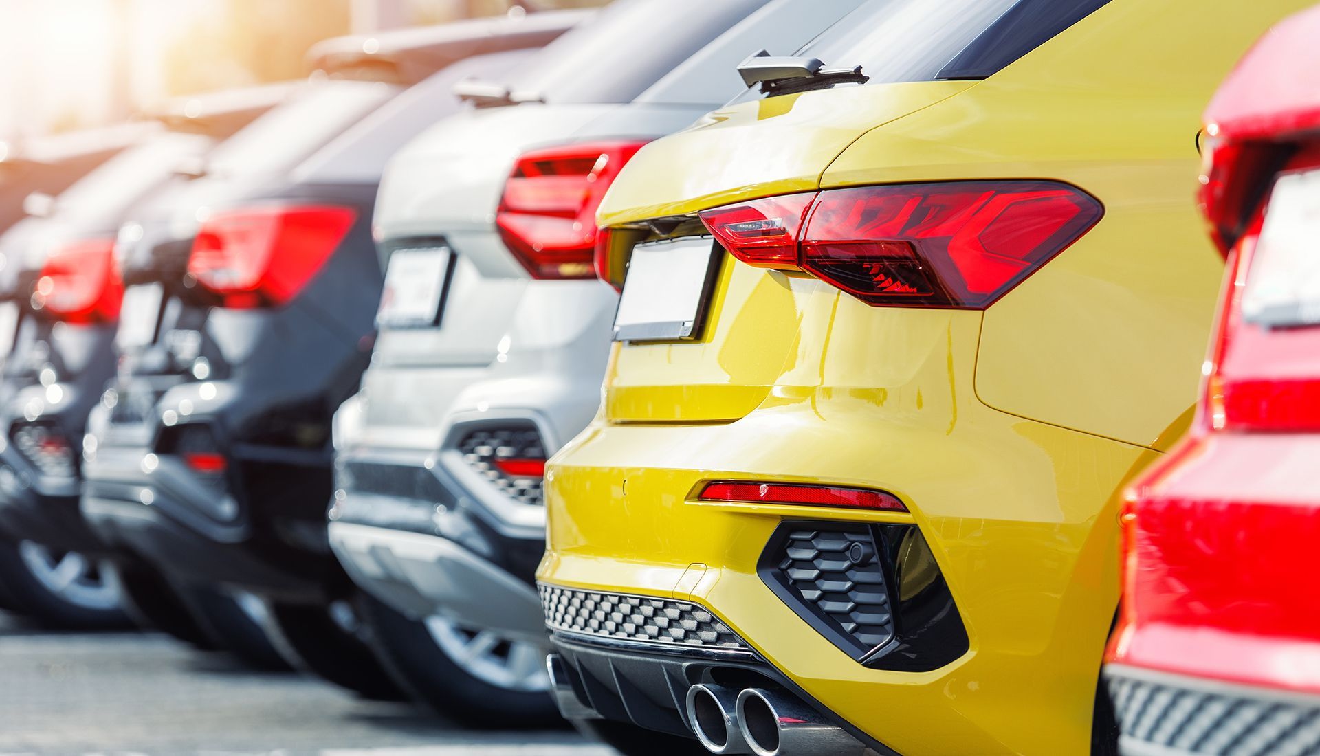 Cars parked in a row, varying colors including yellow, black, silver, and red.