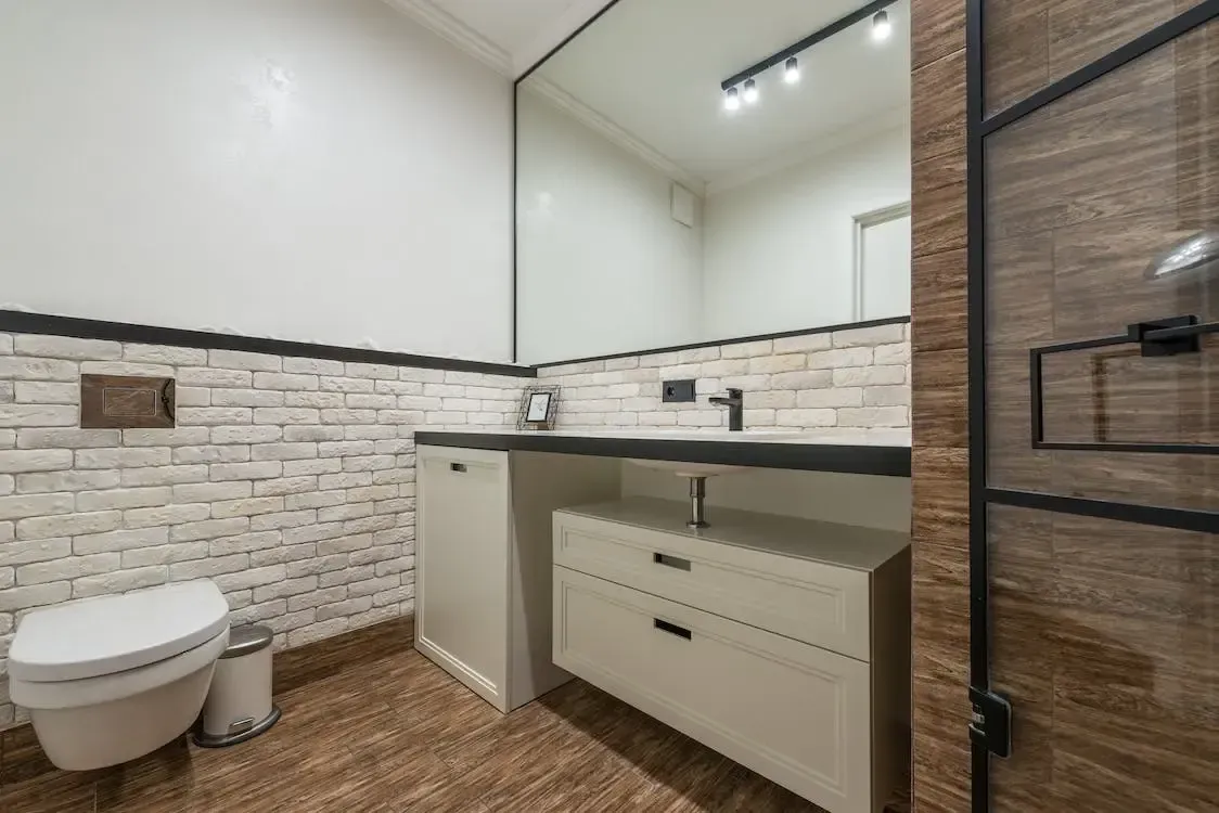 A bathroom with a toilet , sink and mirror.